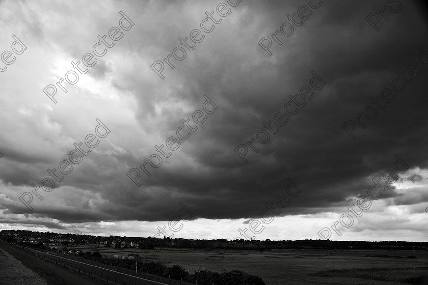 UK Norfolk DSC 0035 
 Stormy clouds above Wells-next-the-sea North Norfolk coast, United Kingdom 
 Keywords: area, clouds, dark, day, field, grass, green, ground, horizon, land, landscape, meadow, nature, Norfolk, perspective, road, rural, scene, sky, storm, stormy, summer, Wells-next-the-sea, view, way, weather,